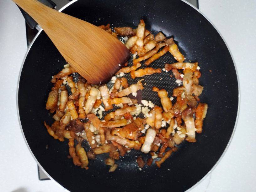 Stif fry the garlic and pork belly by using a wooden spatula.