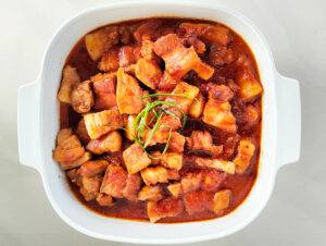 Italian inspired passata braised pork belly garnished in a bowl.