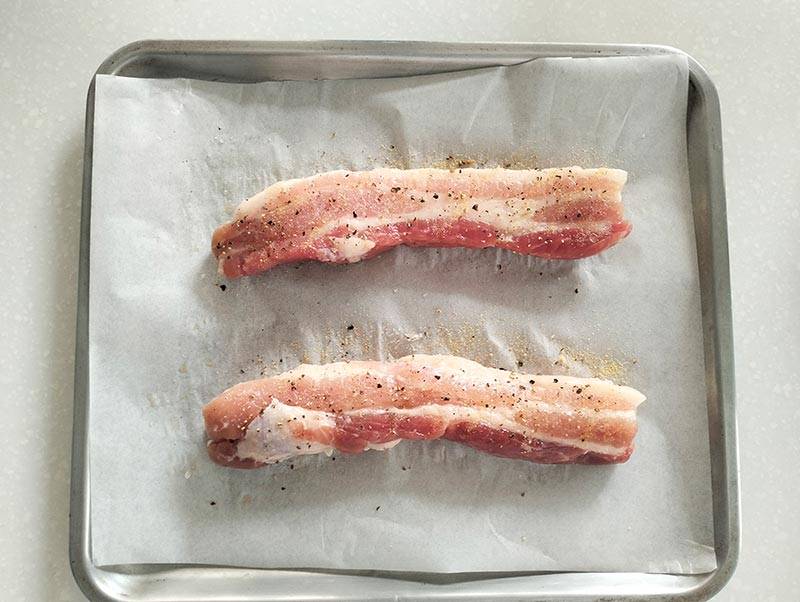 seasoned pork belly placed on a tray with baking paper.