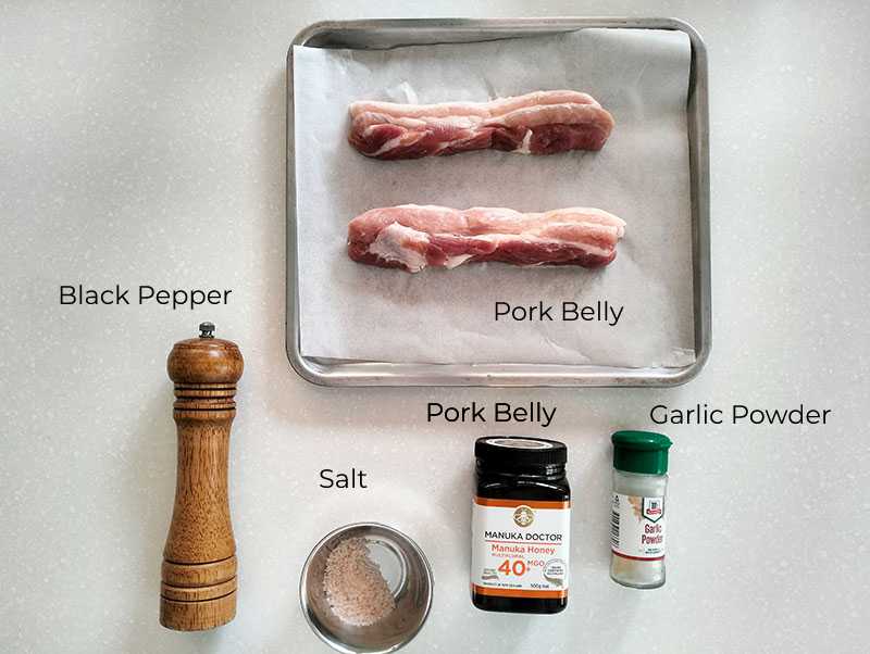 Recipe main ingredients put on the table. The black pepper, salt, garlic powder, honey, and pork belly.
