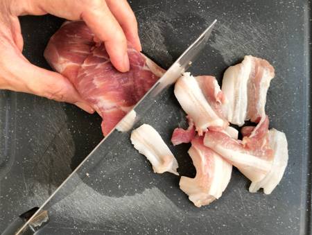 slicing pork belly on cutting board